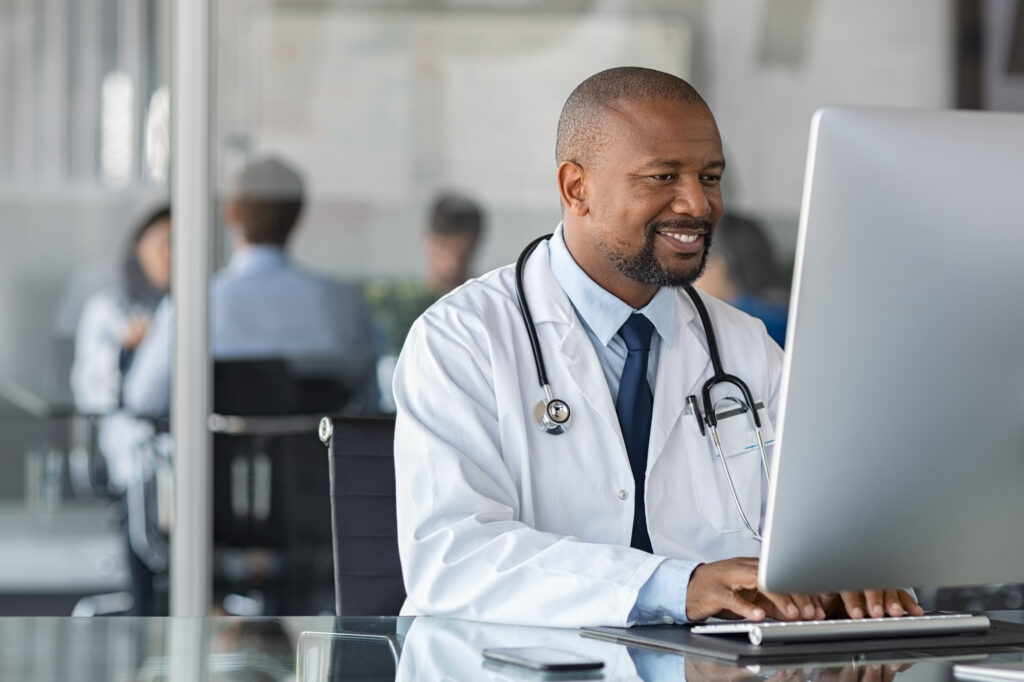 A doctor at his computer reviewing patient records.